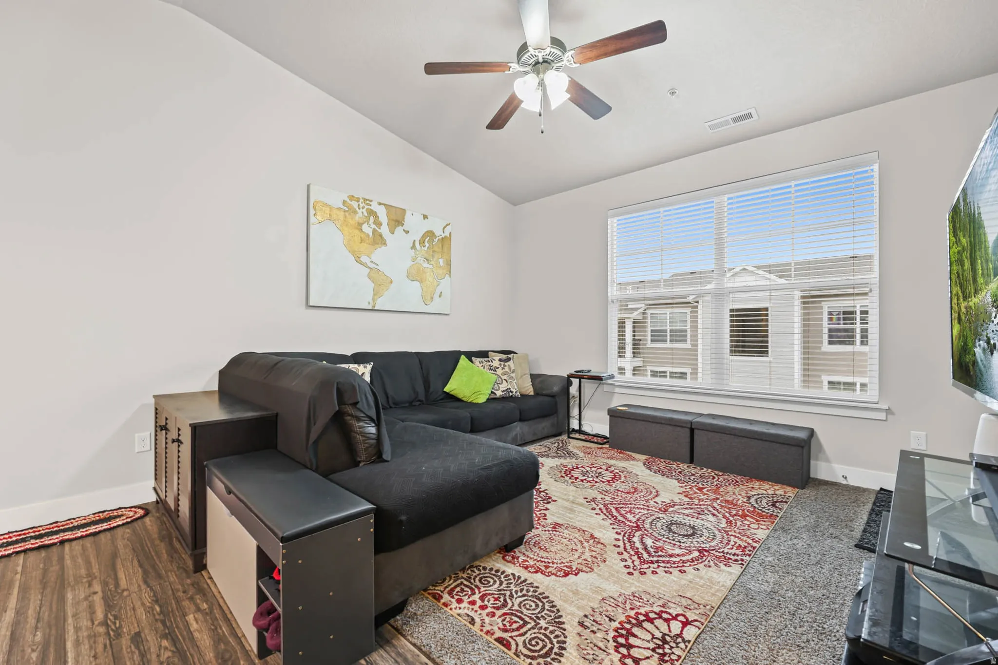 Living room featuring a ceiling fan, wood finished floors, and vaulted ceiling