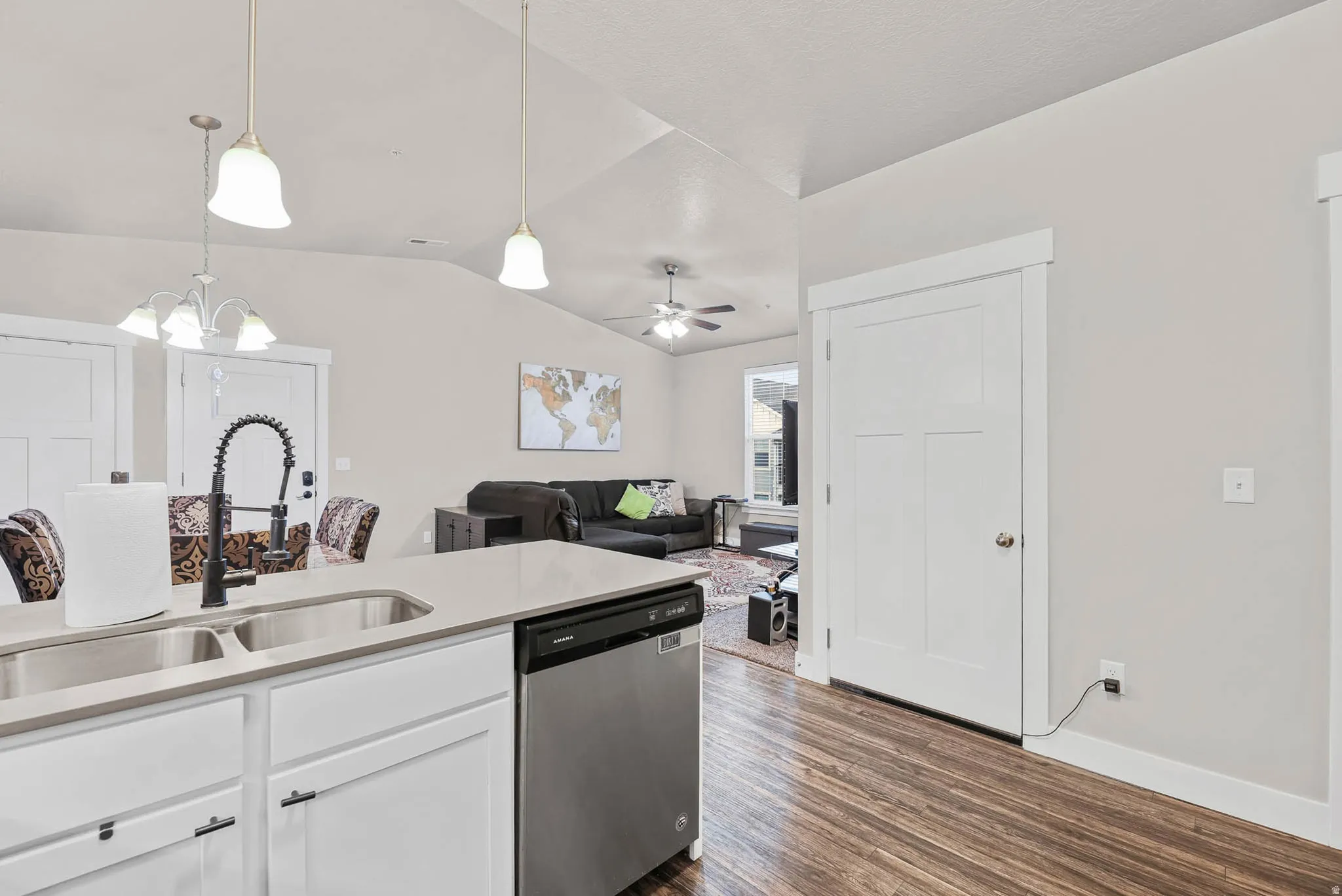 Kitchen with stainless steel dishwasher, open floor plan, dark wood-type flooring, light stone countertops, and white cabinetry