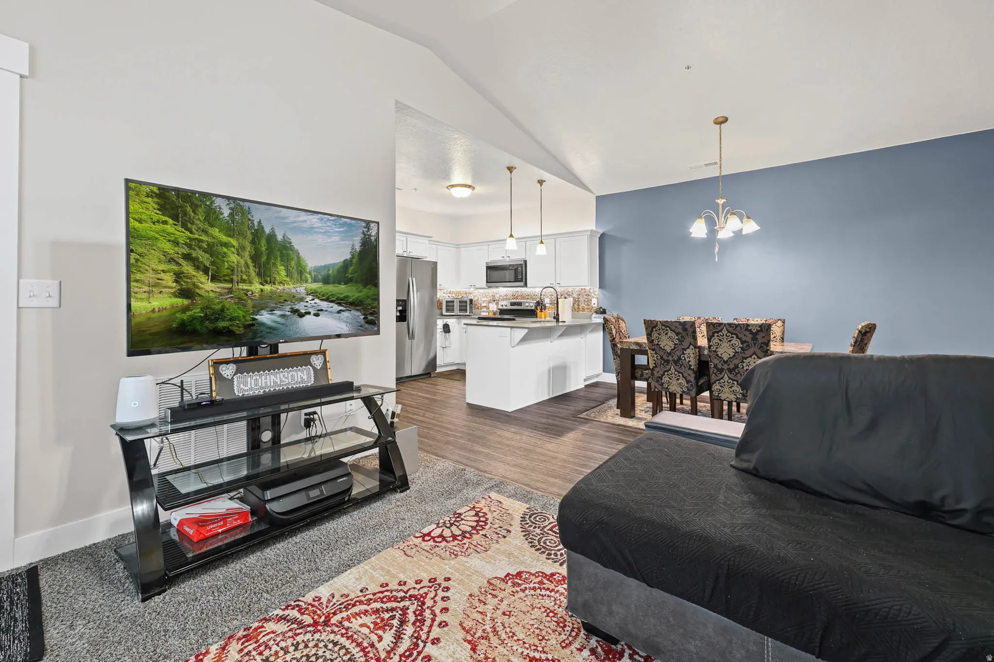Living room featuring suspended lighting, lofted ceiling, and dark wood-style floors