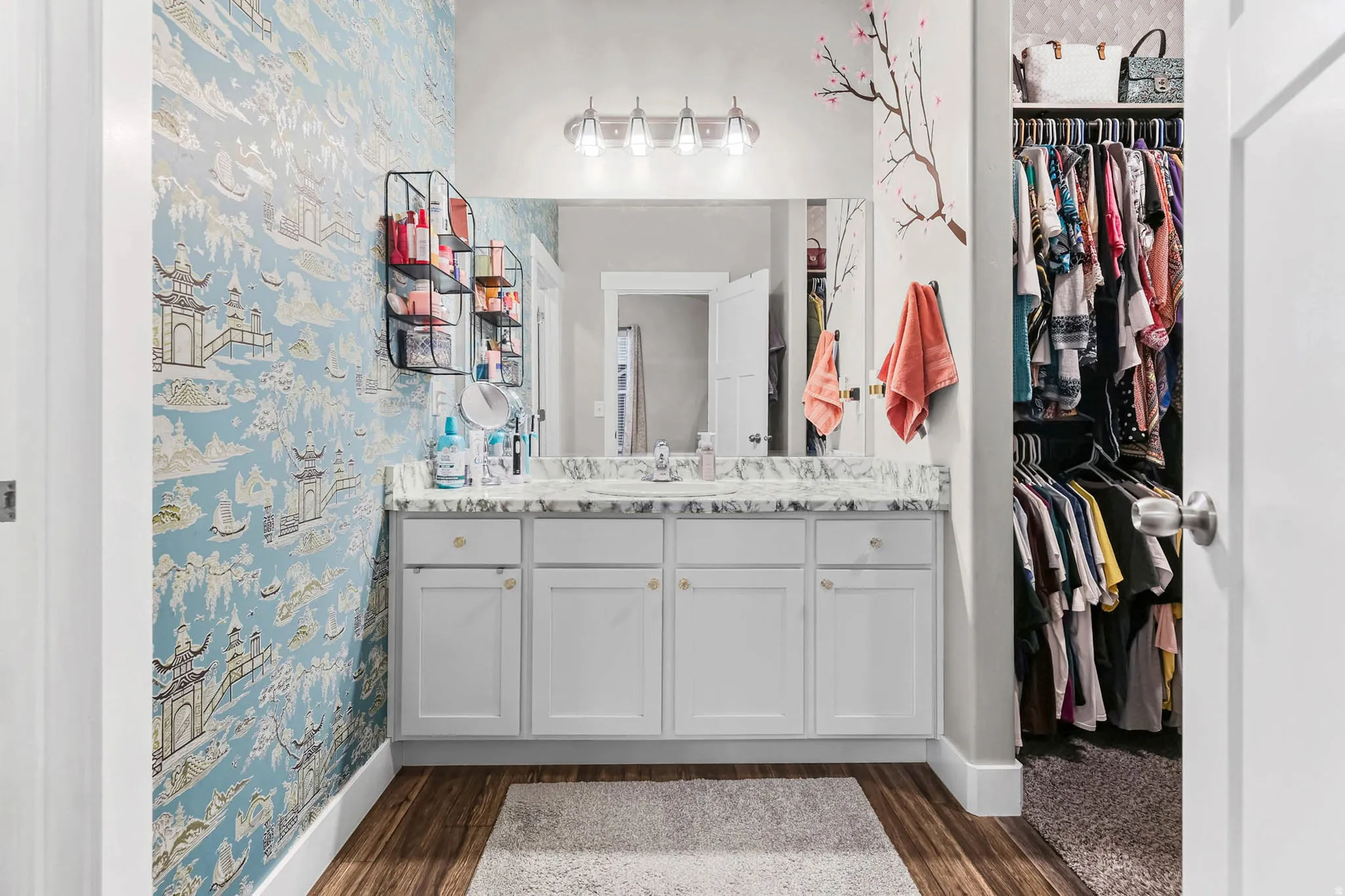 Bathroom featuring vanity, a walk in closet, dark wood-type flooring, and wallpapered walls