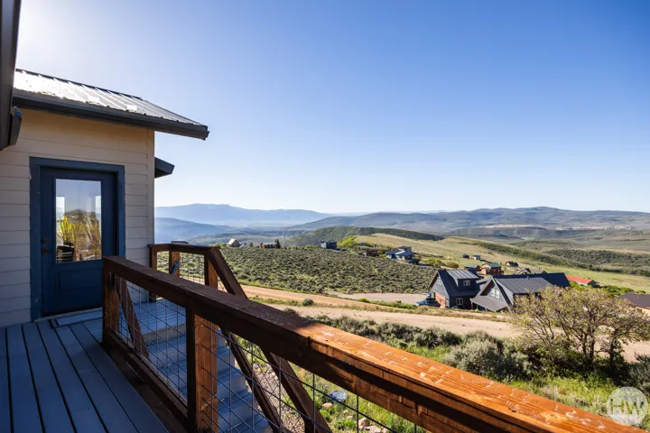 Outdoor deck with wood-finish railing and mesh infill, offering expansive mountain range scenery