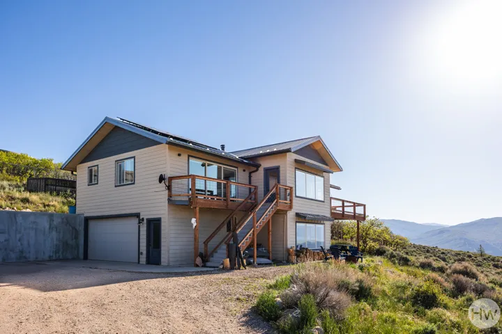 Contemporary two-story residence with a concrete retaining wall, attached garage, and multiple outdoor decks