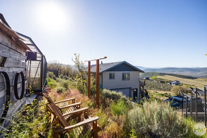 Hillside property featuring a detached rustic shed with glass paneling, wood-plank siding, and decorative metal rings