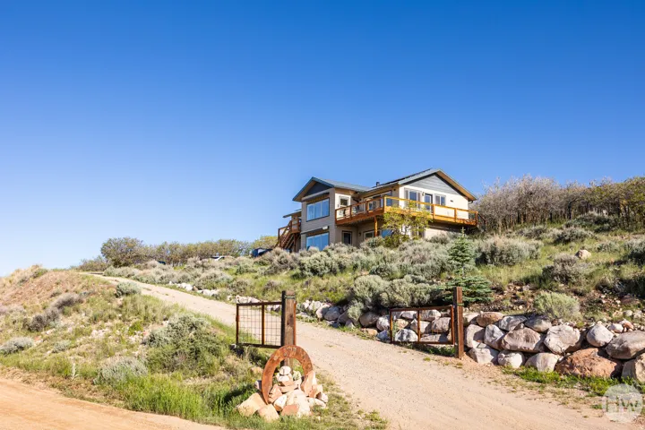 Multi-level residence featuring a prominent balcony, an expansive deck, and large windows