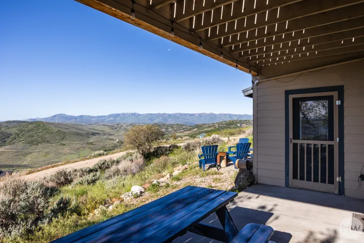 Covered patio area with a concrete floor, featuring a screen door and a slatted wood ceiling
