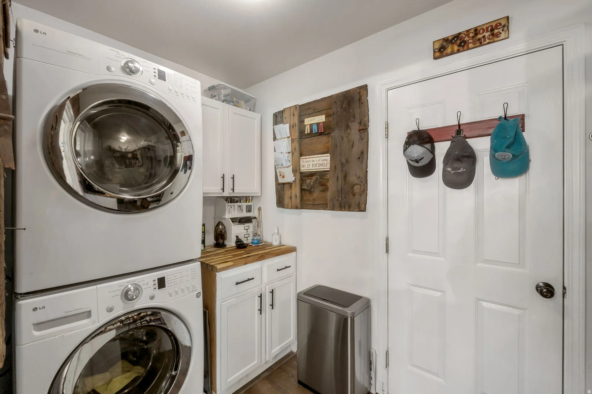Laundry room featuring cabinet space, stacked washer and clothes dryer, and dark wood finished floors