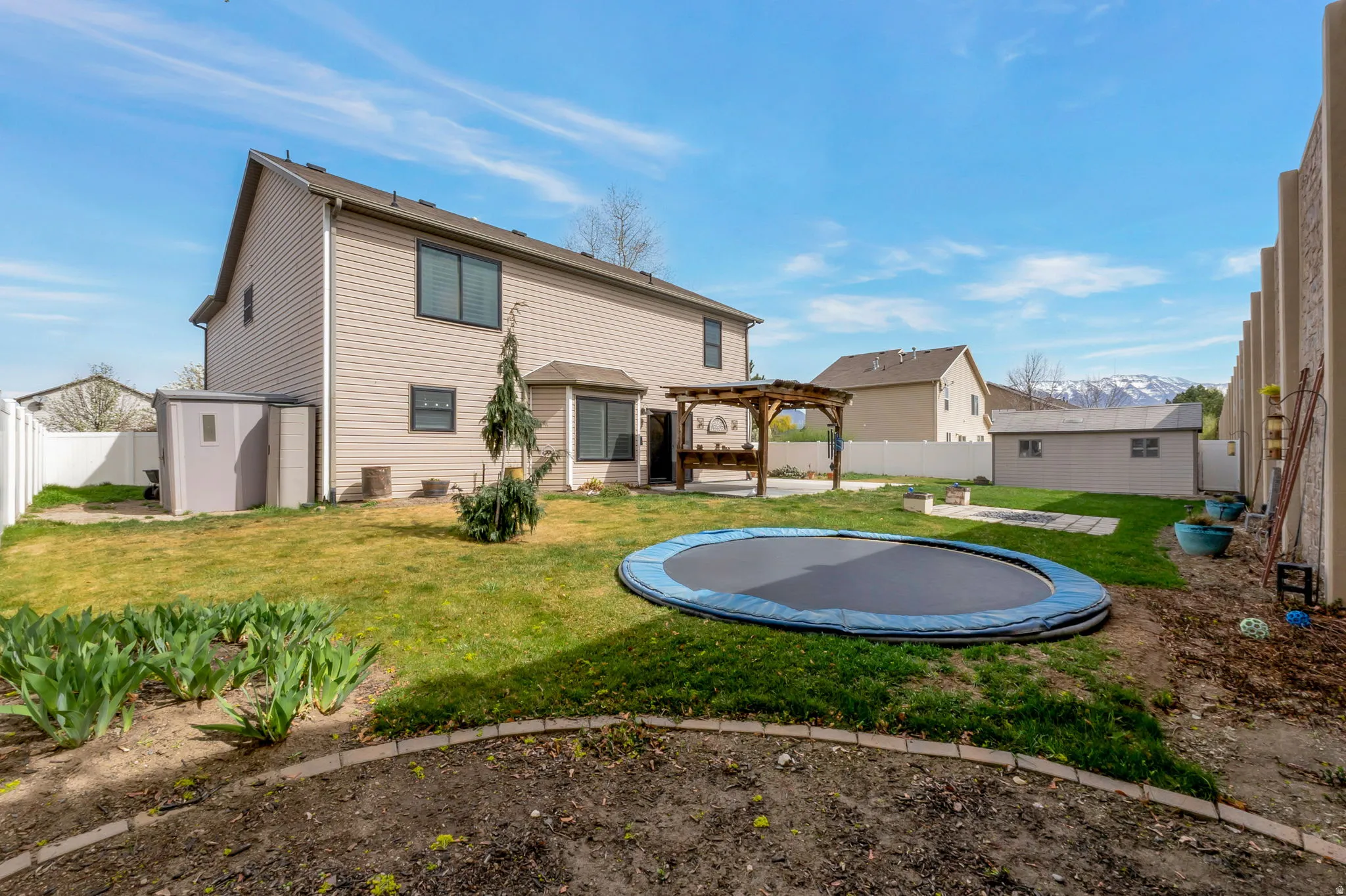 Back of house featuring a pergola, a patio area, a fenced backyard, a shed, and a trampoline