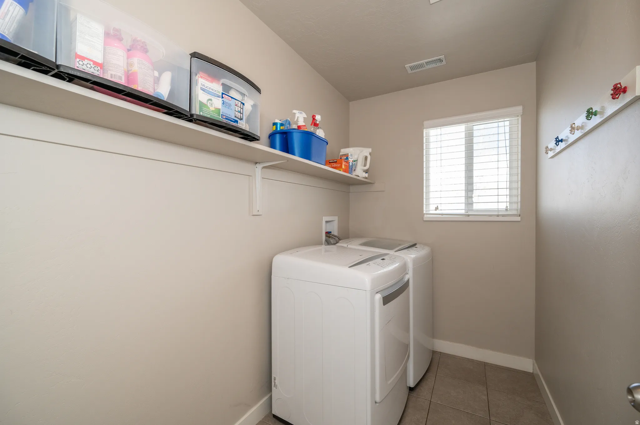 Laundry area with light tile patterned floors and washer and clothes dryer