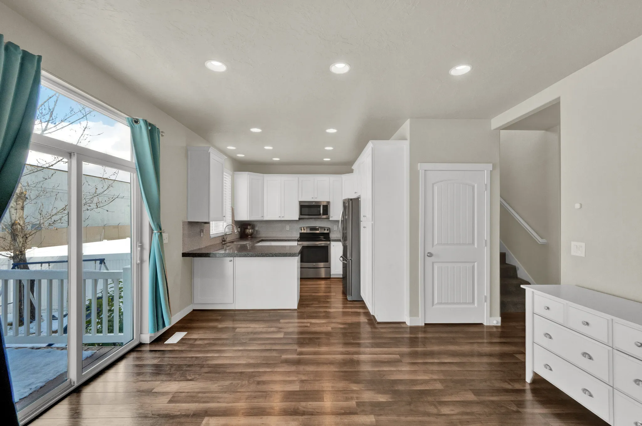 Kitchen featuring white cabinetry, recessed lighting, a peninsula, stainless steel appliances, and dark wood-type flooring