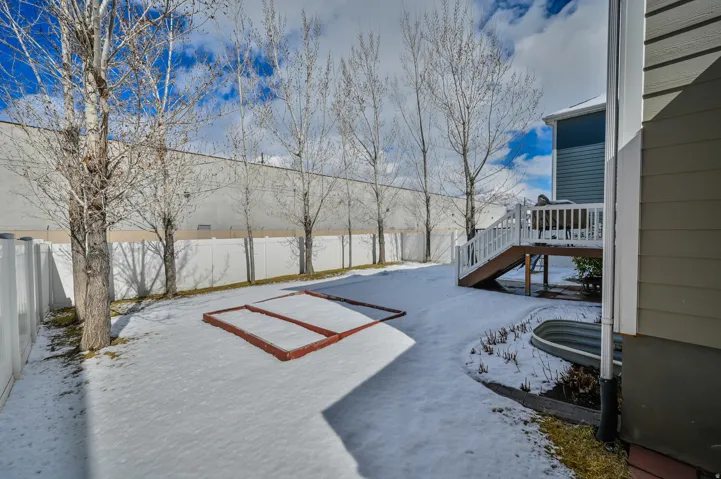 Snowy yard with a fenced backyard and a wooden deck
