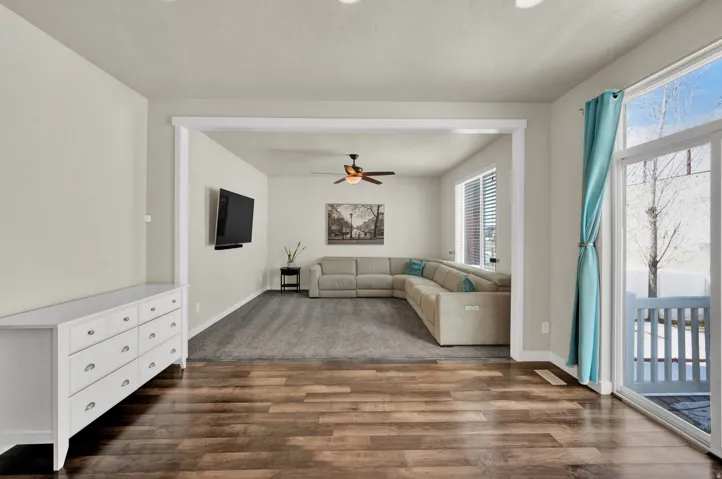Unfurnished living room featuring ceiling fan and dark wood-type flooring