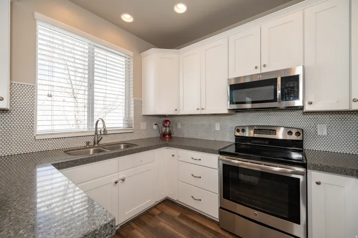 Kitchen featuring stainless steel appliances, white cabinetry, recessed lighting, dark wood-style floors, and dark stone countertops
