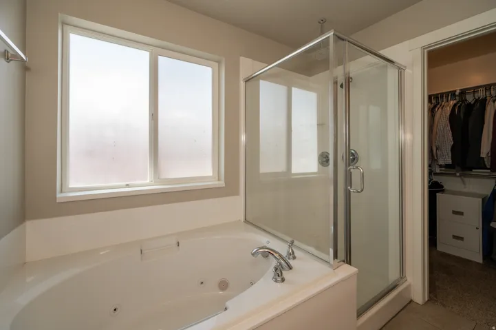 Full bathroom featuring a walk in closet, a shower stall, and a whirlpool tub
