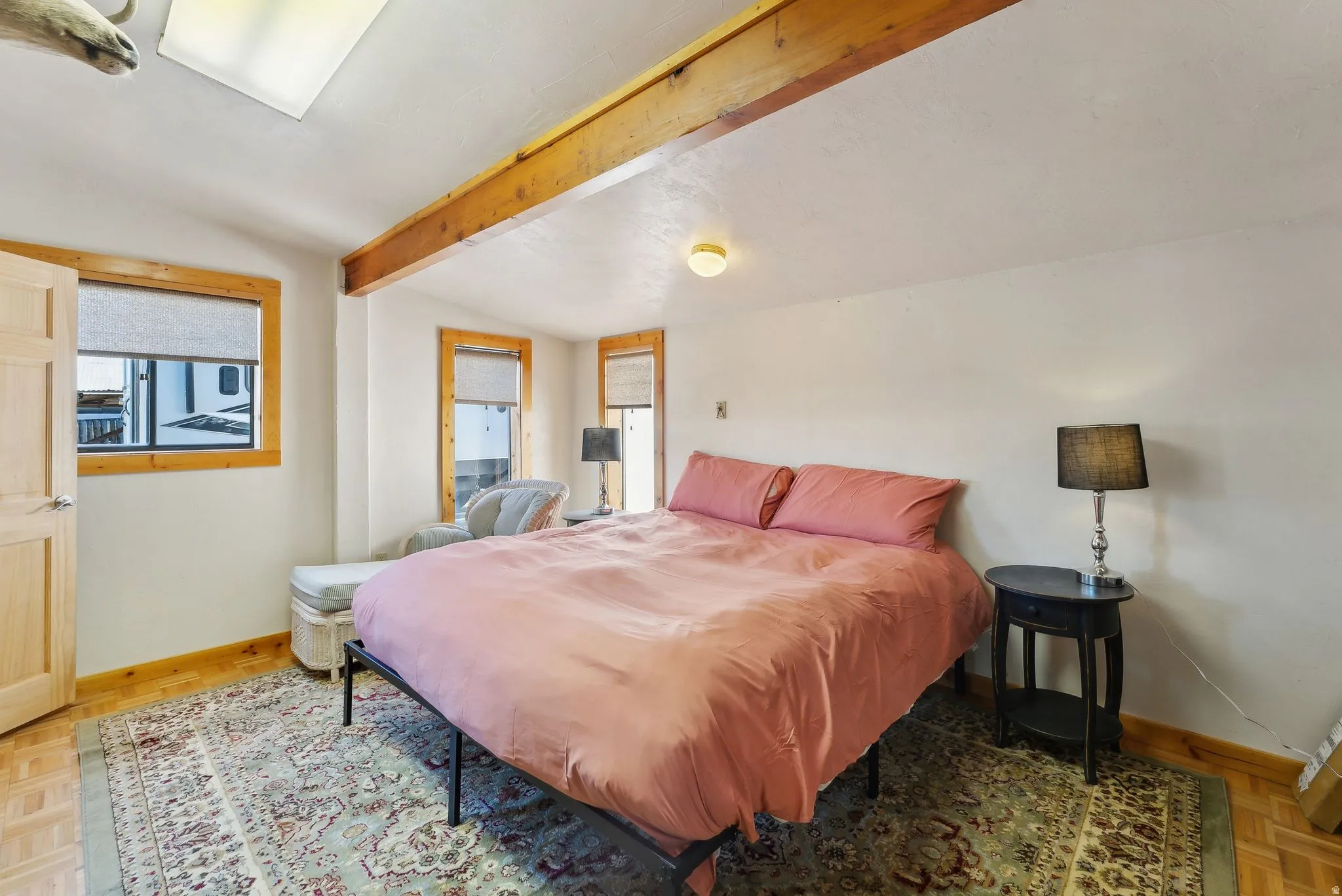 Bedroom with parquet floors, vaulted ceiling with beams, and multiple windows