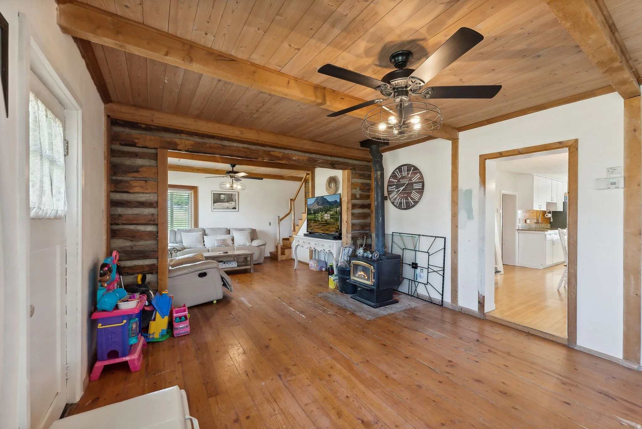 Playroom featuring a wood stove, wood-type flooring, a ceiling fan, and a wooden ceiling with exposed beams