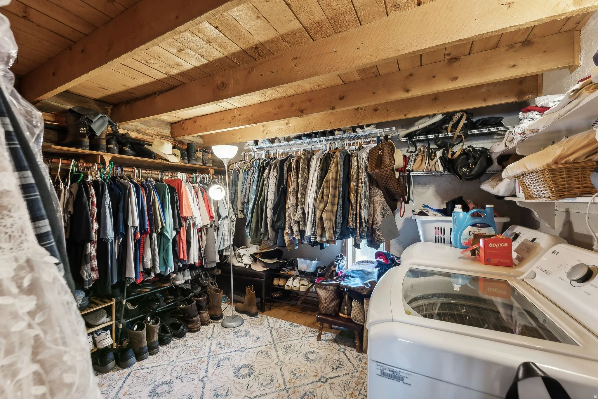 Walk in closet featuring washer and clothes dryer, beamed ceiling, and light wood finished floors