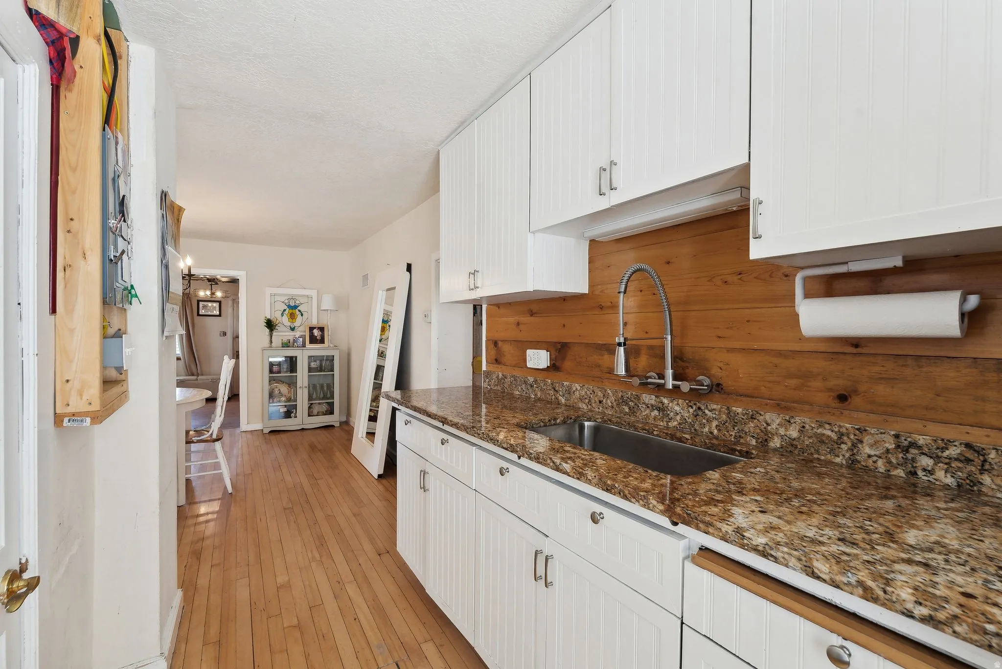 Kitchen featuring white cabinetry, dark stone countertops, light wood-type flooring, and a textured ceiling
