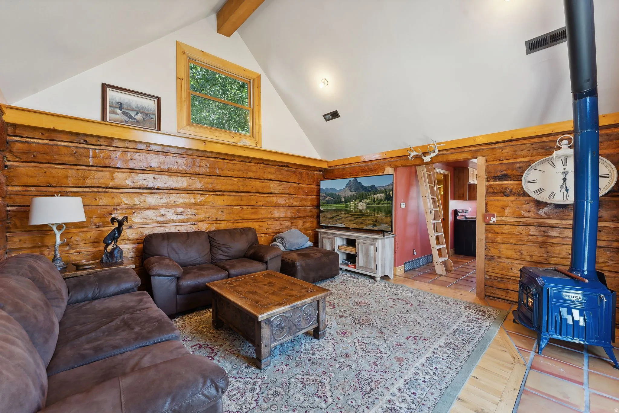 Living room featuring log walls, a wood stove, and wood finished floors