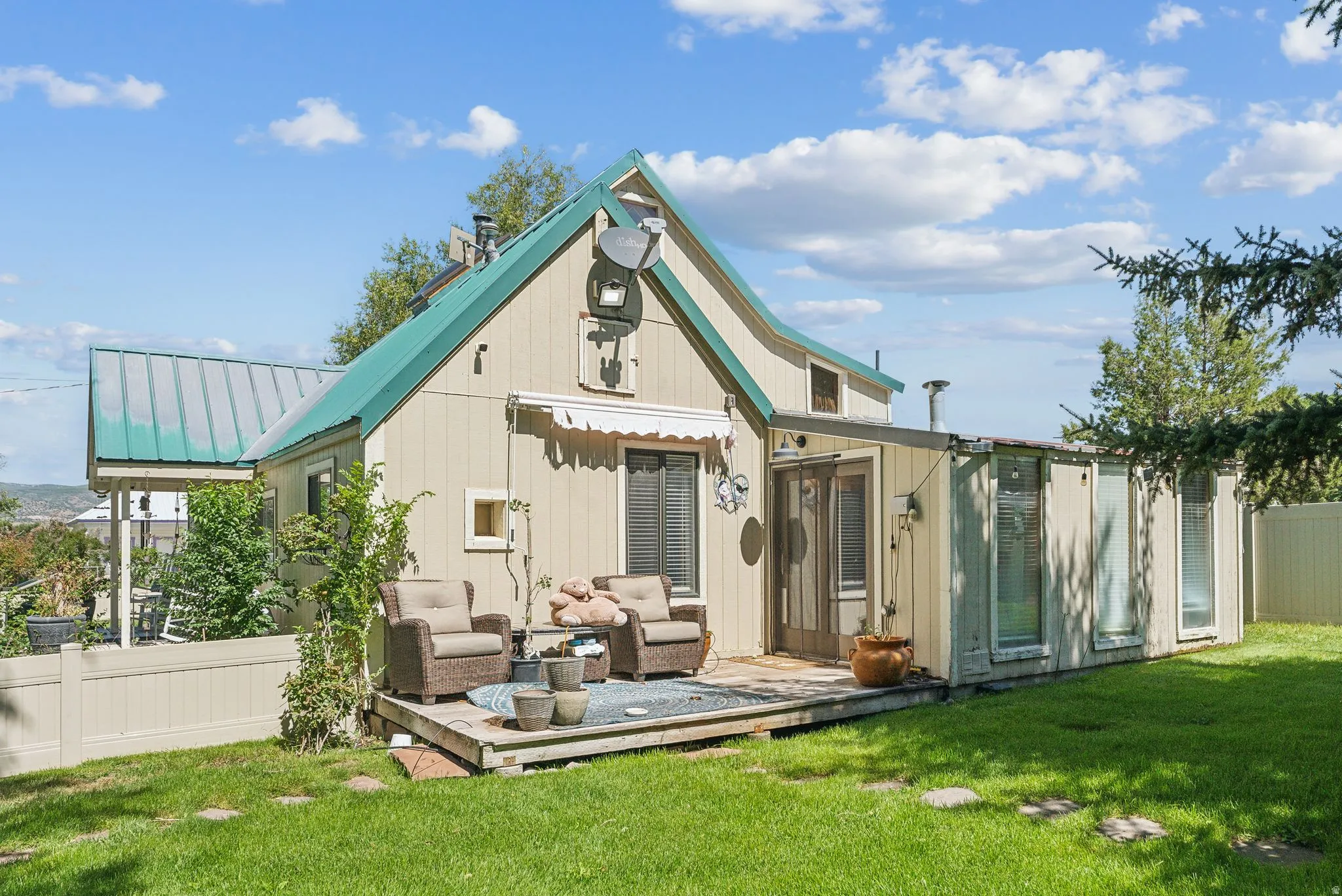 Back of property featuring a wooden deck, outdoor furniture, and a metal roof