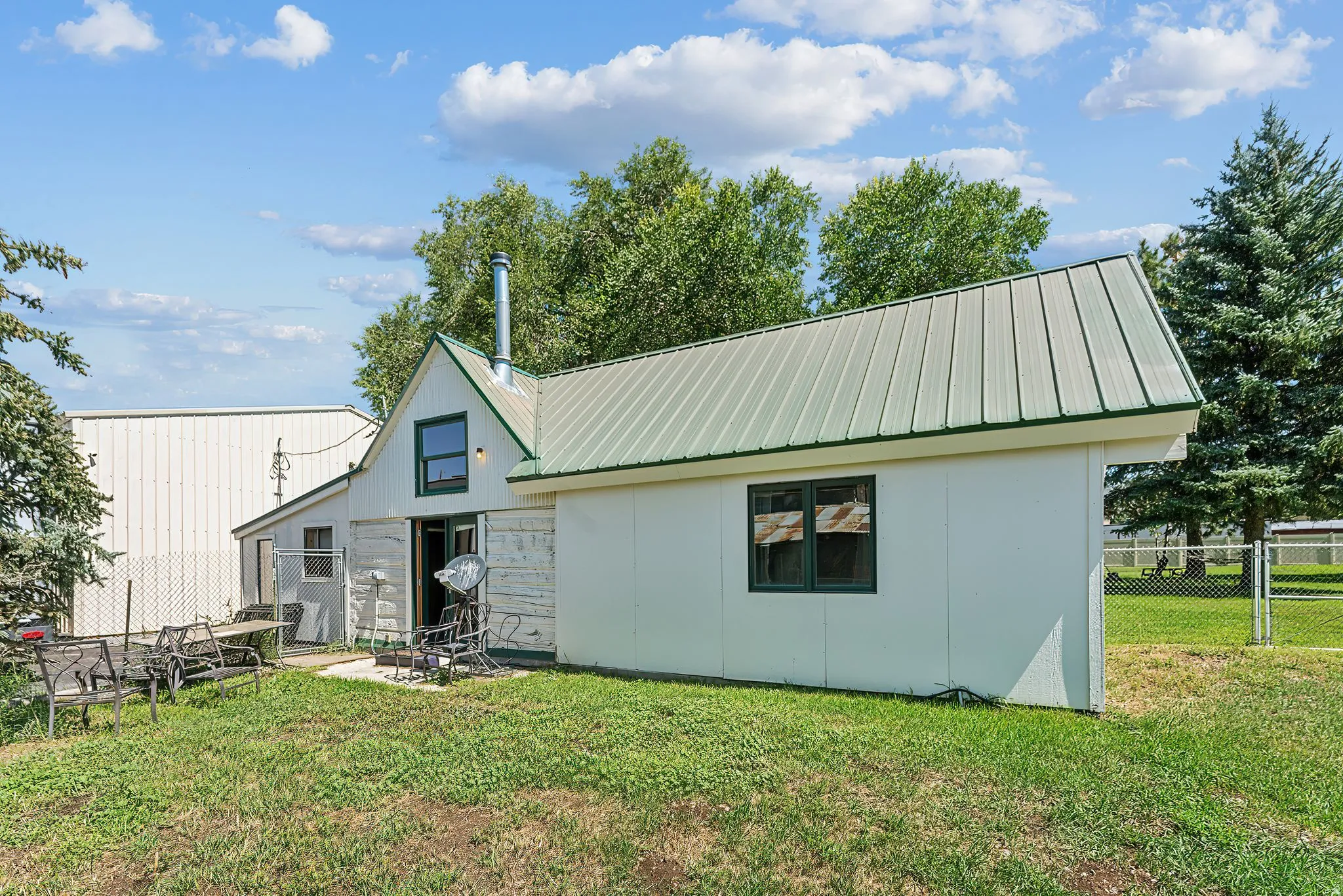 Rear view of house with a metal roof and stone siding