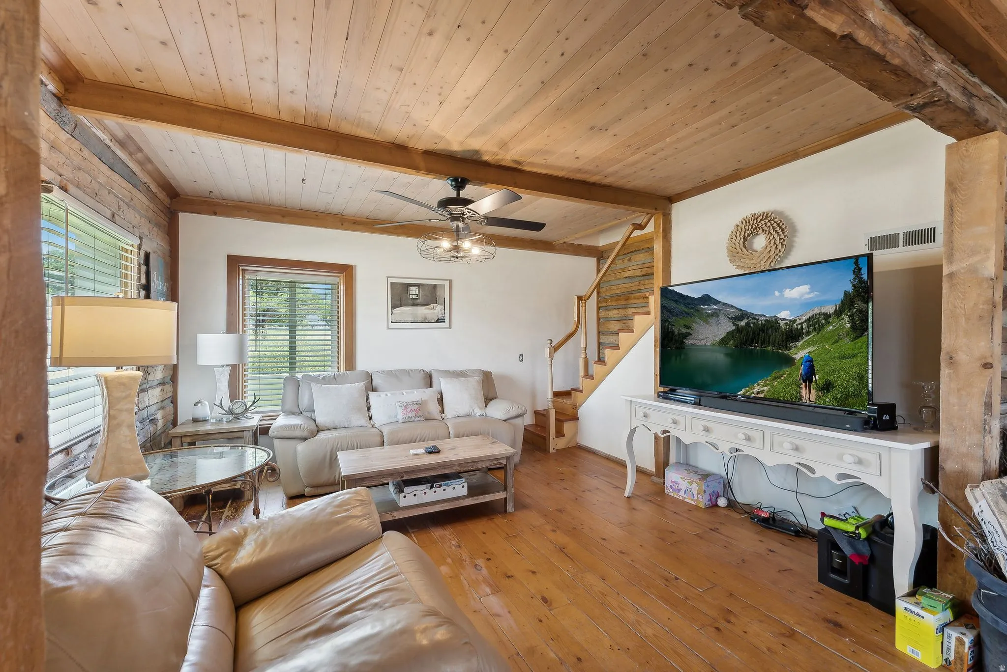 Living room with a ceiling fan, hardwood / wood-style floors, and a wood ceiling with exposed beams