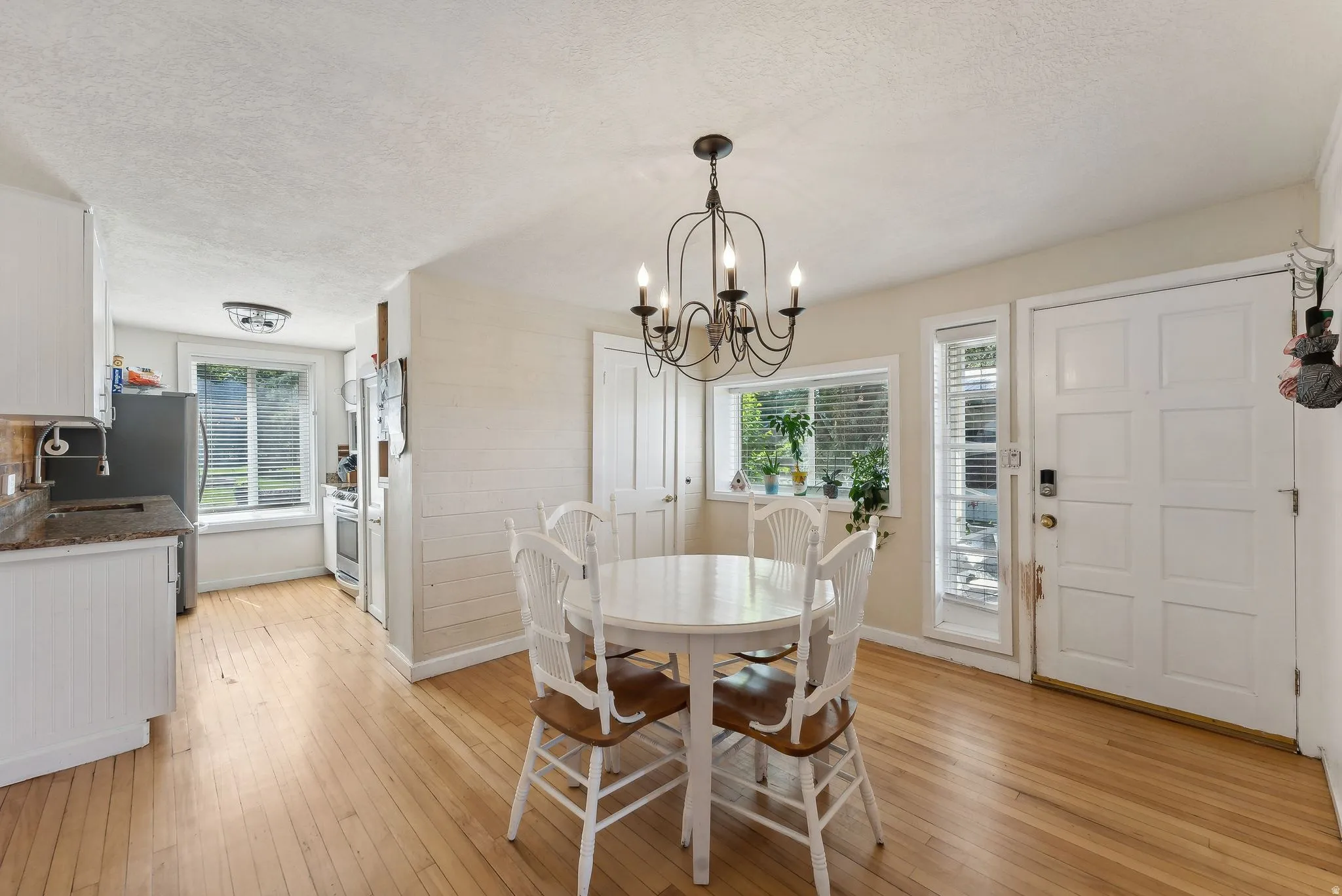 Dining space featuring a textured ceiling, light wood-style flooring, a chandelier, and plenty of natural light