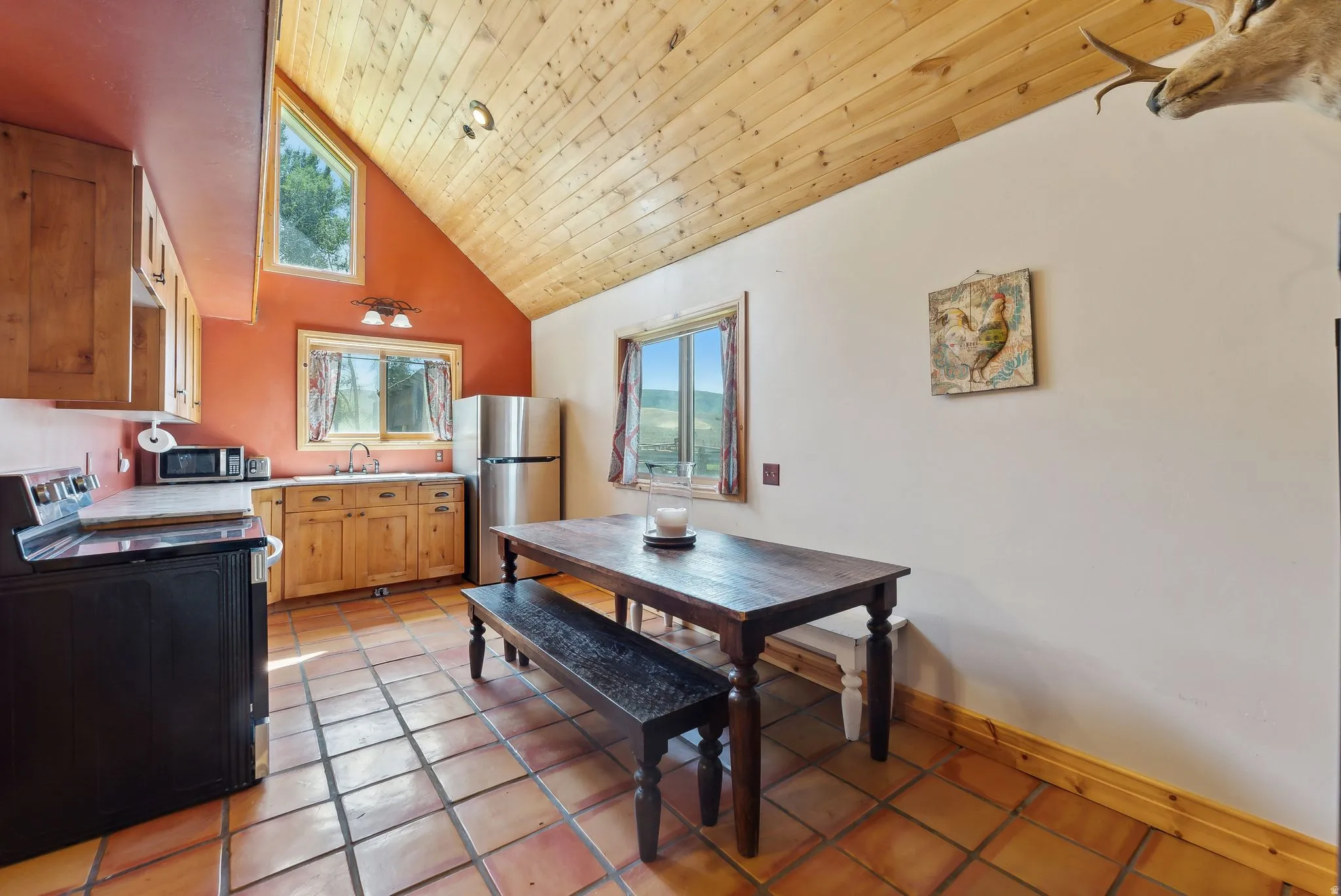 Kitchen featuring stainless steel appliances, a vaulted wood ceiling, light countertops, light tile patterned floors, and wood finish cabinetry