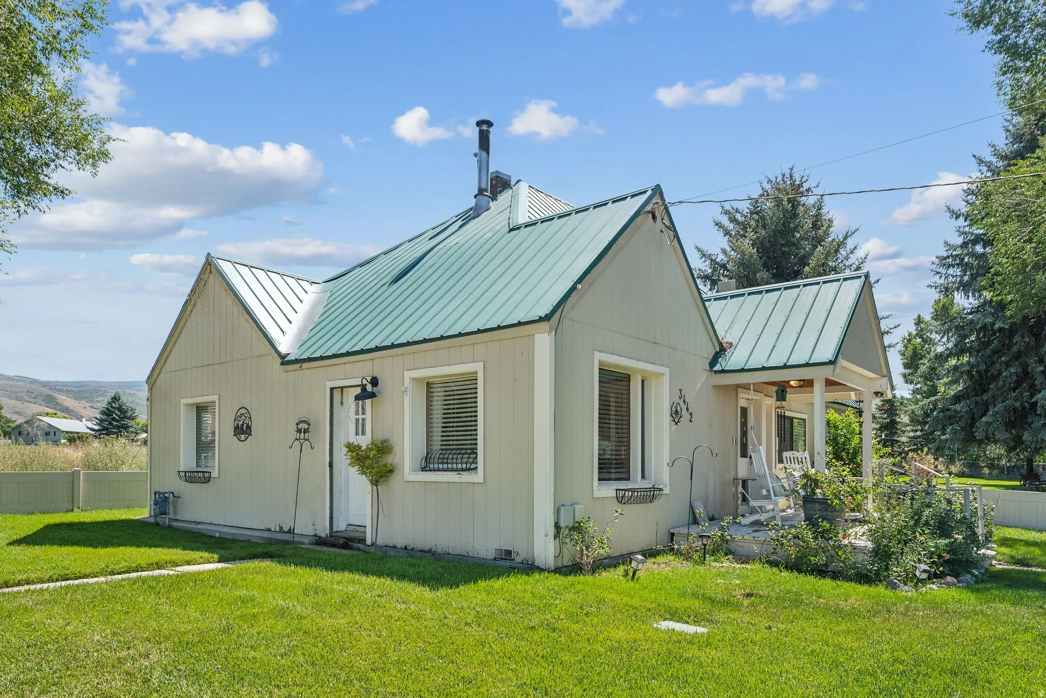 View of front of home with a metal roof, a chimney, and a porch