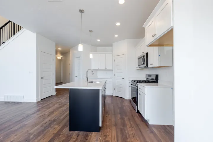 Open-concept kitchen with a central island, white cabinetry, stainless steel appliances, and wood-finish flooring