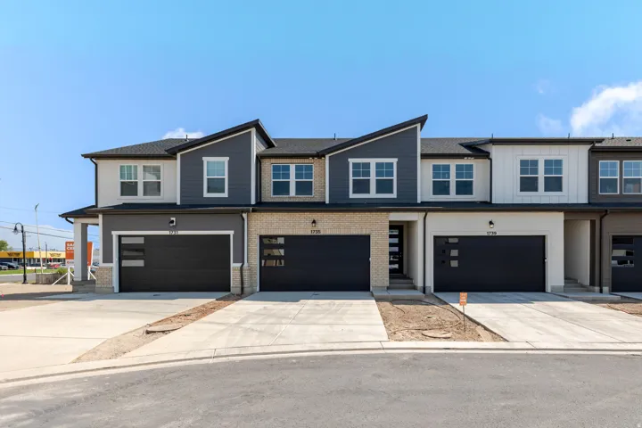 Modern townhome exteriors featuring varied siding, brick accents, and black garage doors with frosted window inserts