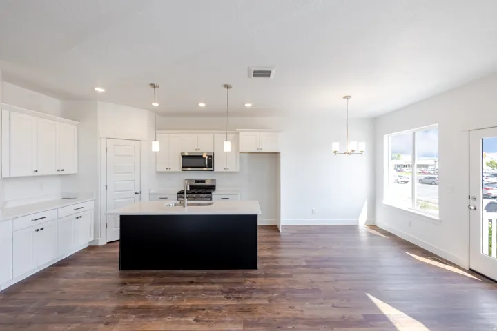 Spacious kitchen featuring white cabinetry, a large center island, stainless steel appliances, and recessed lighting