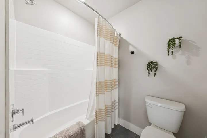 Bathroom featuring shower / tub combo with curtain and dark tile patterned floors