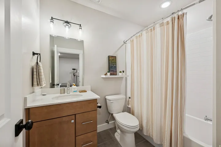 Bathroom with vanity, shower / tub combo, and dark tile patterned flooring