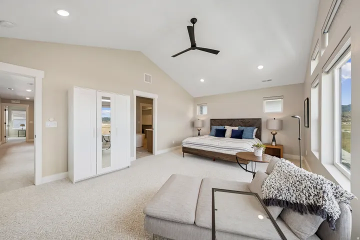 Bedroom with recessed lighting, ensuite bath, light colored carpet, vaulted ceiling, and a ceiling fan