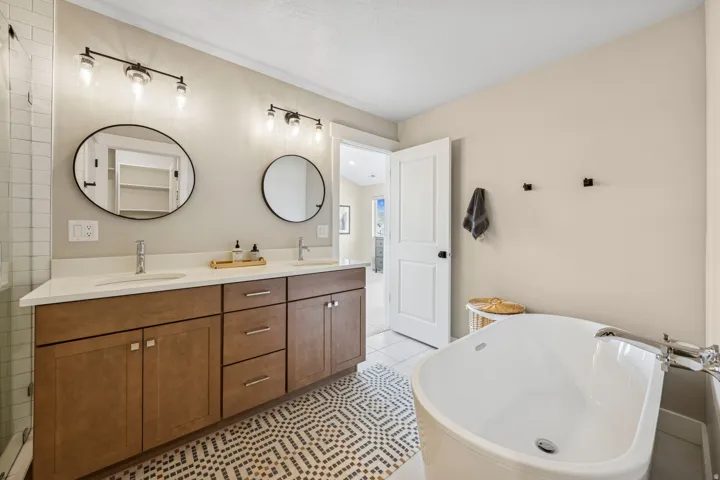 Bathroom with a freestanding tub, double vanity, and light tile patterned floors