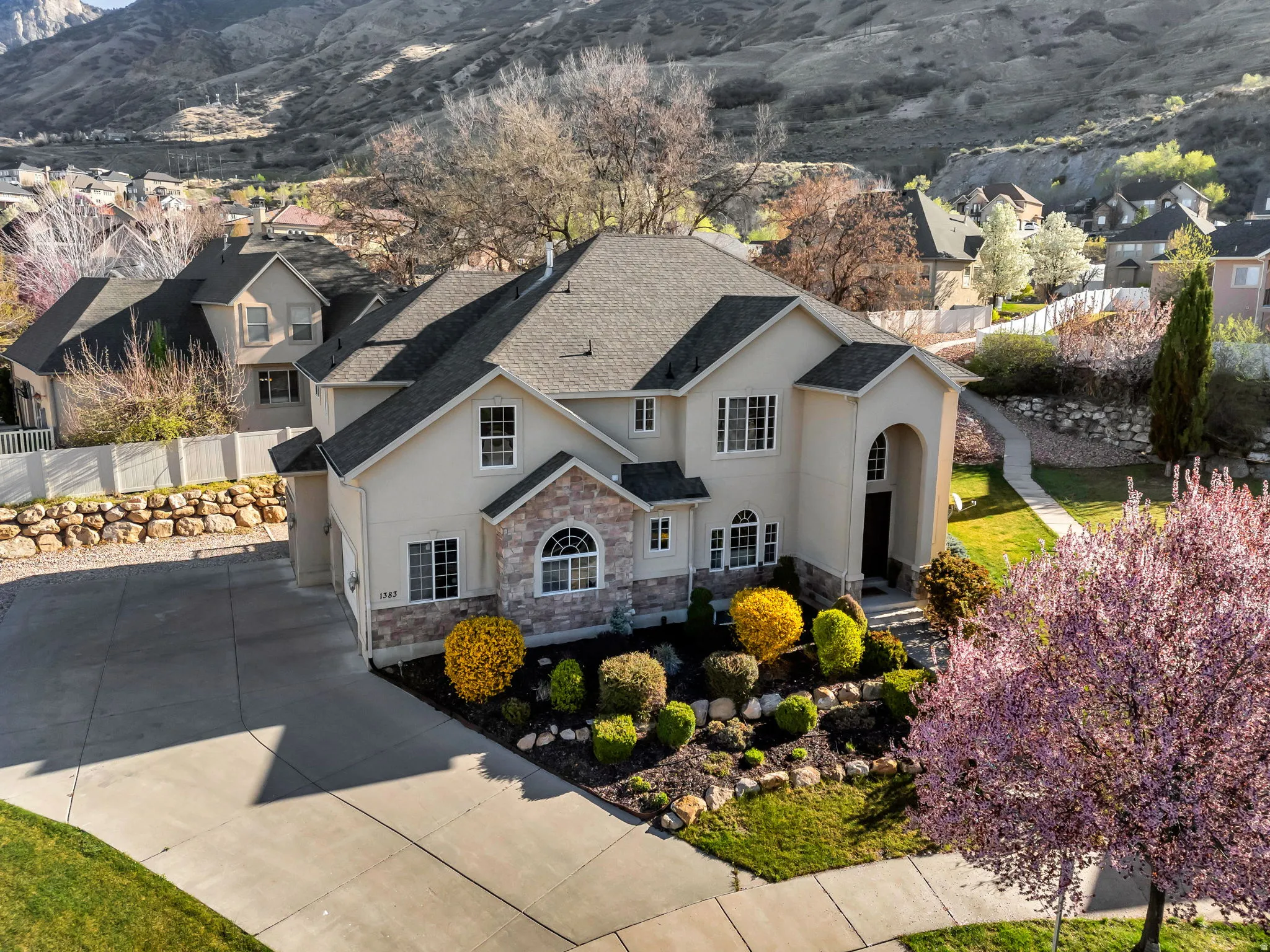 View of front facade with stucco siding, roof with shingles, stone siding, a mountain view, and a residential view