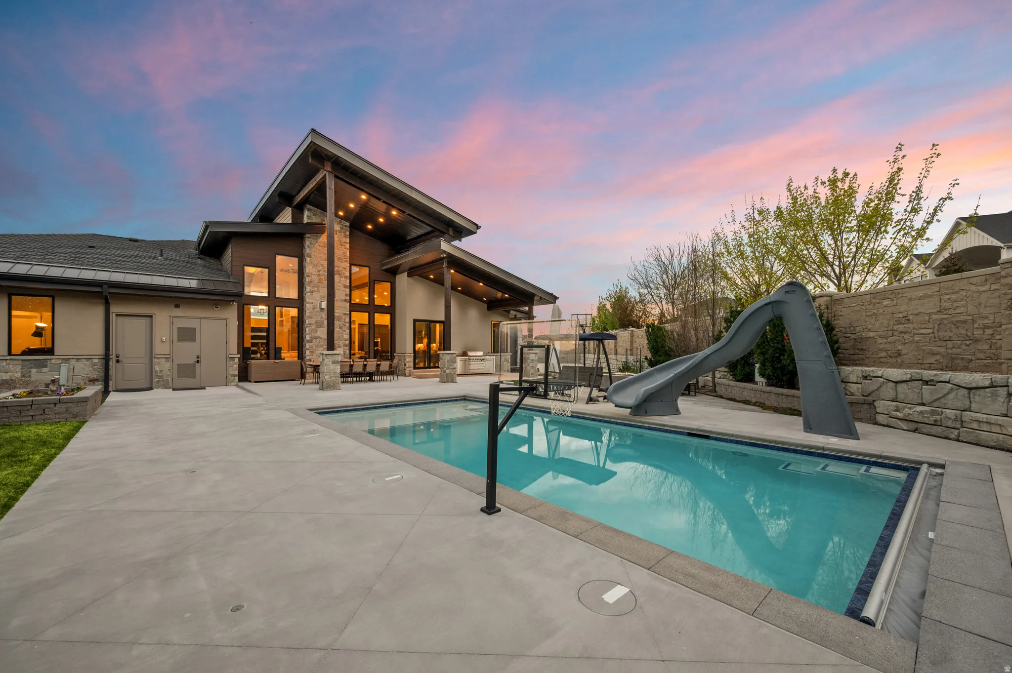 View of swimming pool featuring a water slide, a fenced backyard, and patio surround