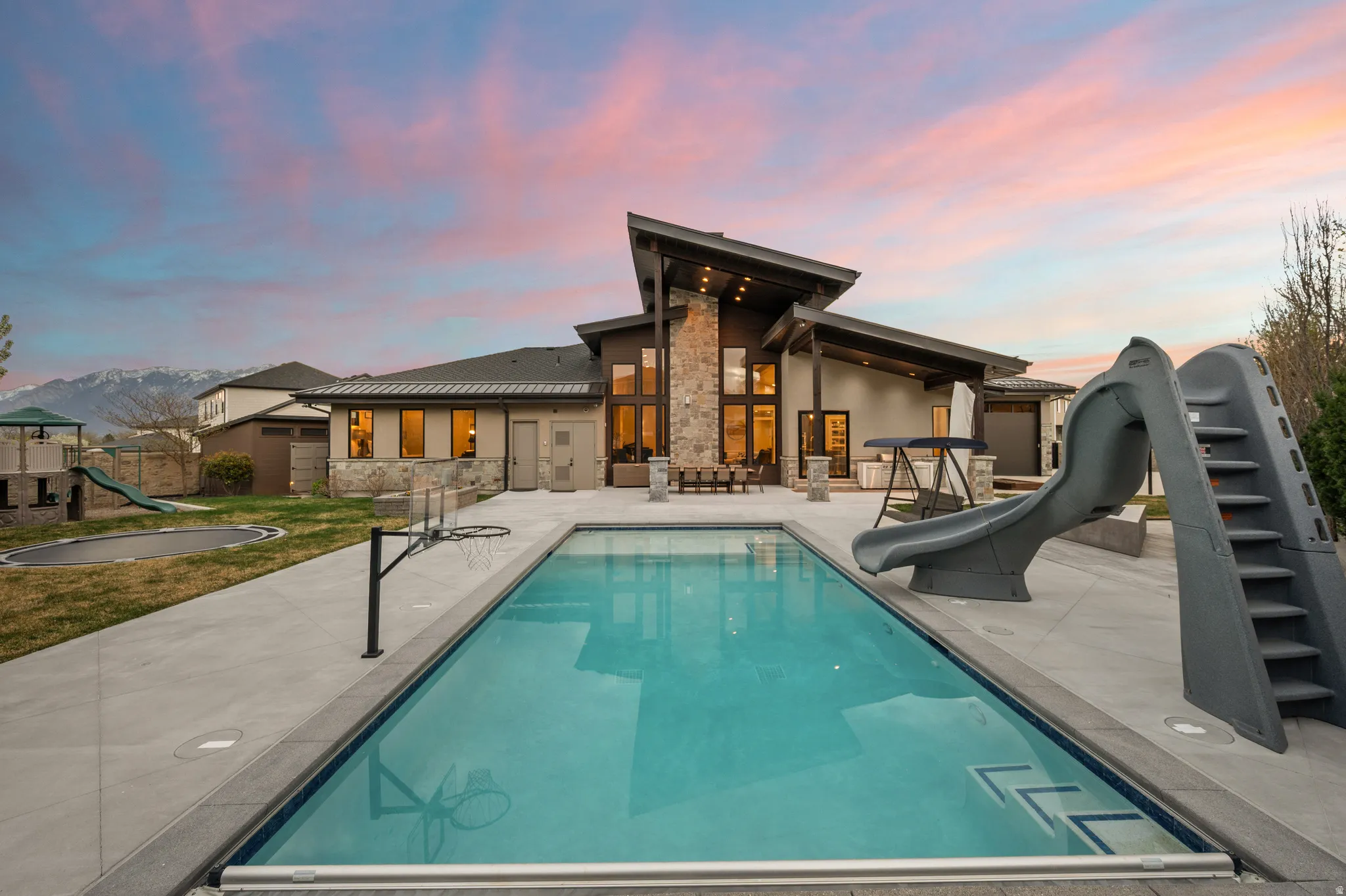 Rear view of property featuring a playground, a patio, and stone siding