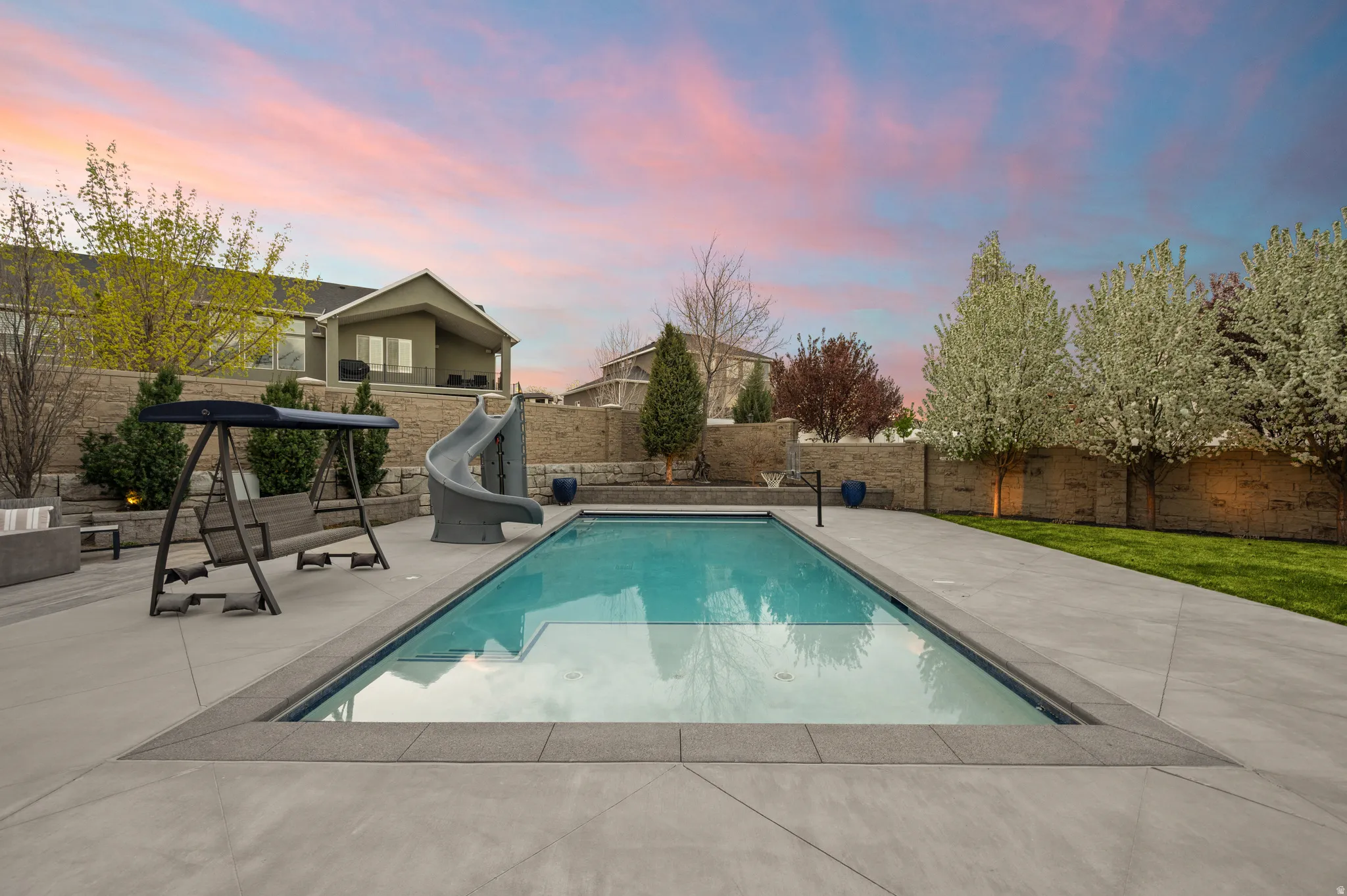 View of swimming pool featuring a water slide, a fenced backyard, and patio surround