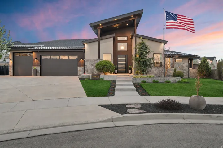 Contemporary home with stone siding, a garage, concrete driveway, and stucco siding