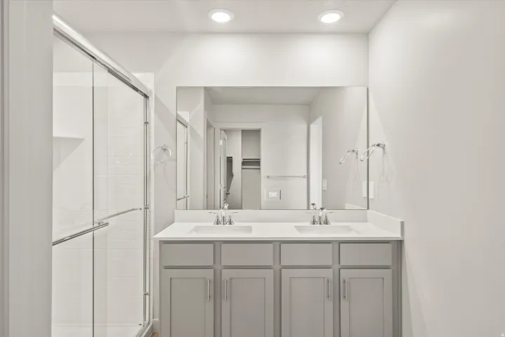 Full bath featuring double vanity, a stall shower, a walk in closet, and recessed lighting