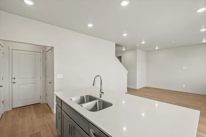 Kitchen with light wood-type flooring, recessed lighting, light stone countertops, gray cabinets, and open floor plan