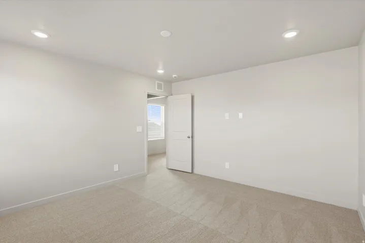 Empty room with light colored carpet and recessed lighting