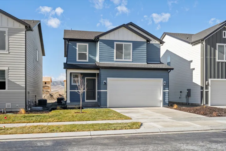 View of front facade featuring board and batten siding, driveway, an attached garage, and a shingled roof