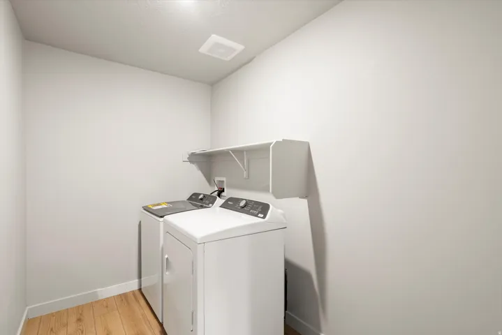 Laundry area featuring washing machine and clothes dryer and light wood-type flooring