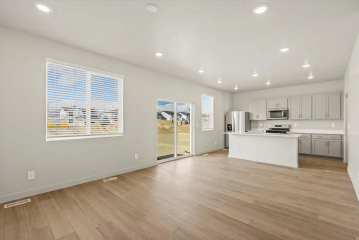 Kitchen featuring light countertops, a kitchen island with sink, gray cabinetry, light wood-style floors, and stainless steel appliances