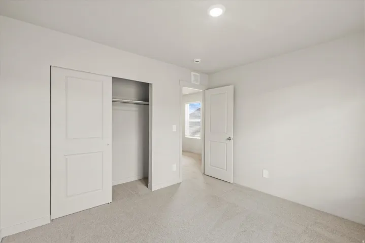 Unfurnished bedroom with light carpet and a closet