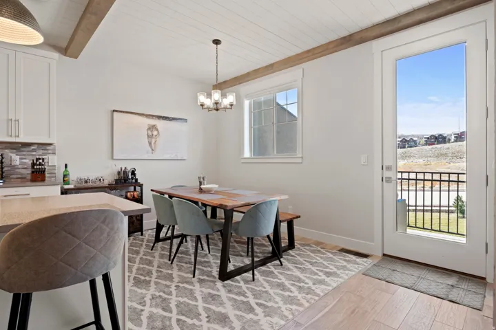 Dining area with light wood-type flooring, suspended lighting, and a wood ceiling with exposed beams