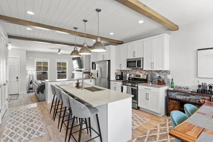 Kitchen featuring stainless steel appliances, a kitchen breakfast bar, tasteful backsplash, decorative light fixtures, and a center island with sink