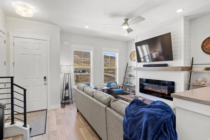 Living area with ceiling fan, light wood-style floors, a glass covered fireplace, and recessed lighting